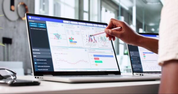 a person using a pen to point at charts on a computer screen