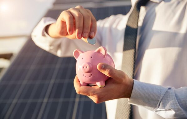 Someone putting a coin into a pink piggybank